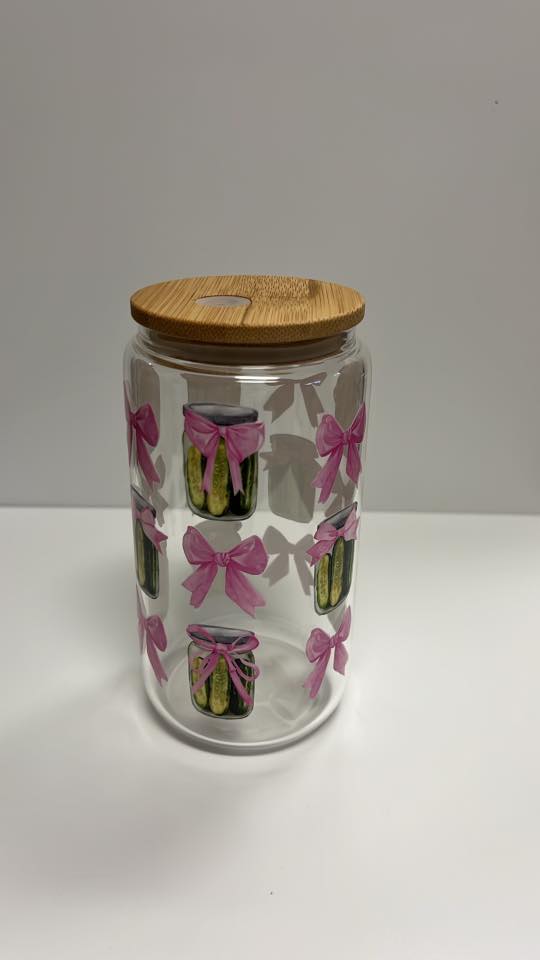 Glass jar with wooden lid featuring pink bows and small images on a white background