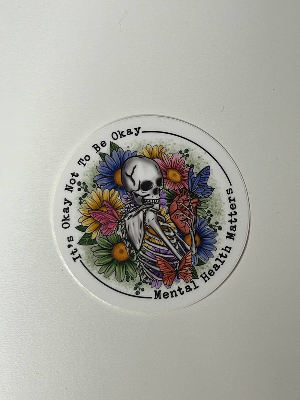 Circular sticker with a skeleton and flowers on a white background