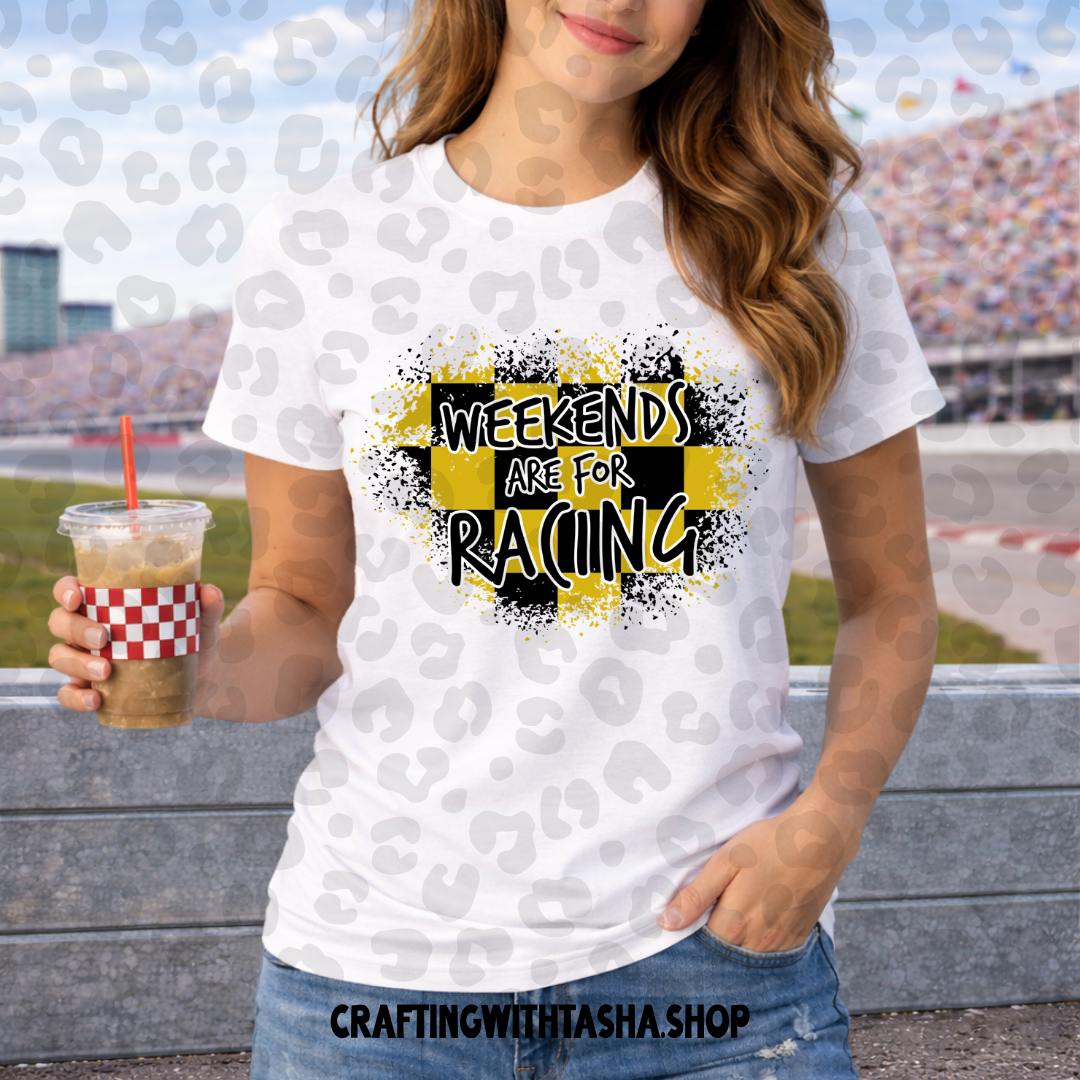 Person wearing a white t-shirt with 'Weekends are for Racing' design, holding a drink at a race track.