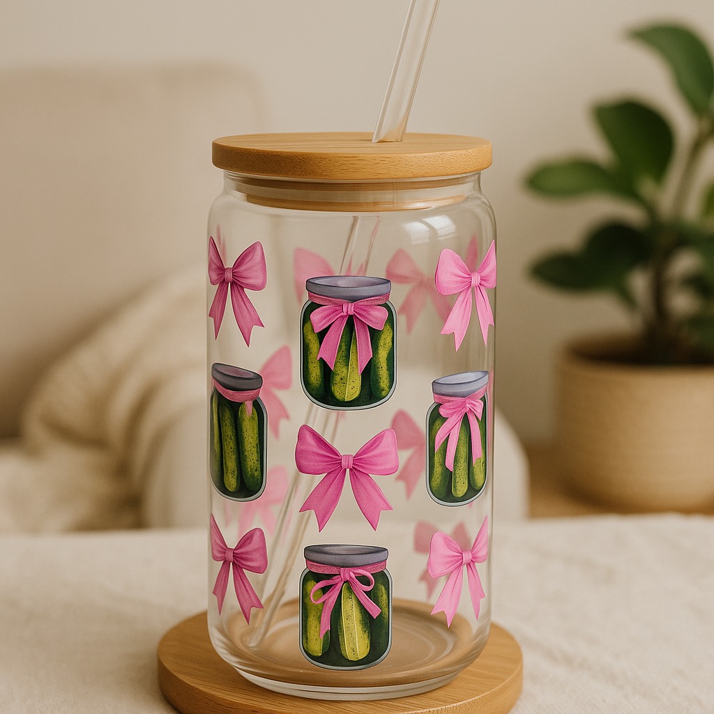 Glass tumbler with pickle design and pink bows on a wooden coaster.